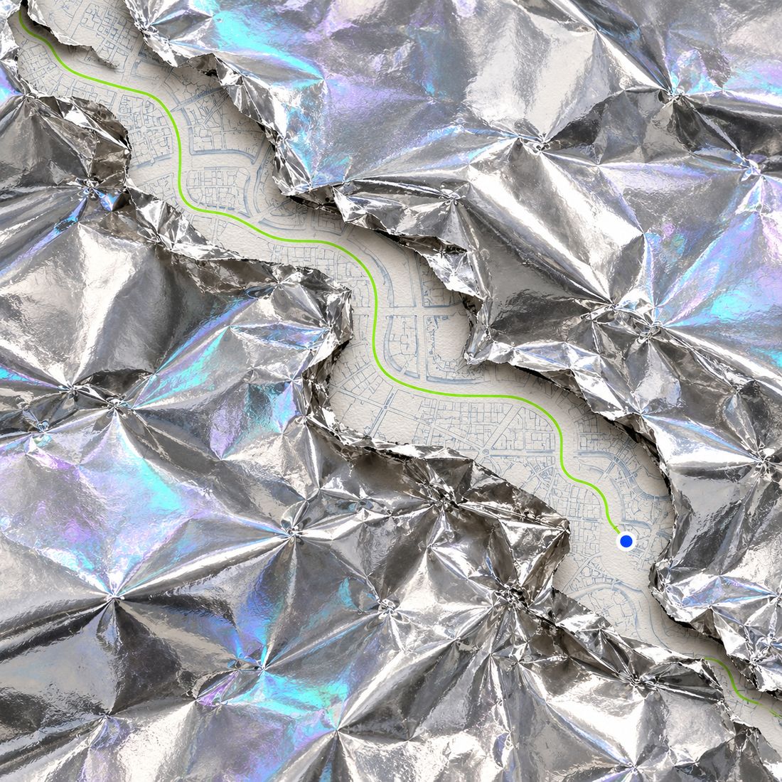 A green route and a blue dot on a paper map, showing through a tear in crumpled holographic foil