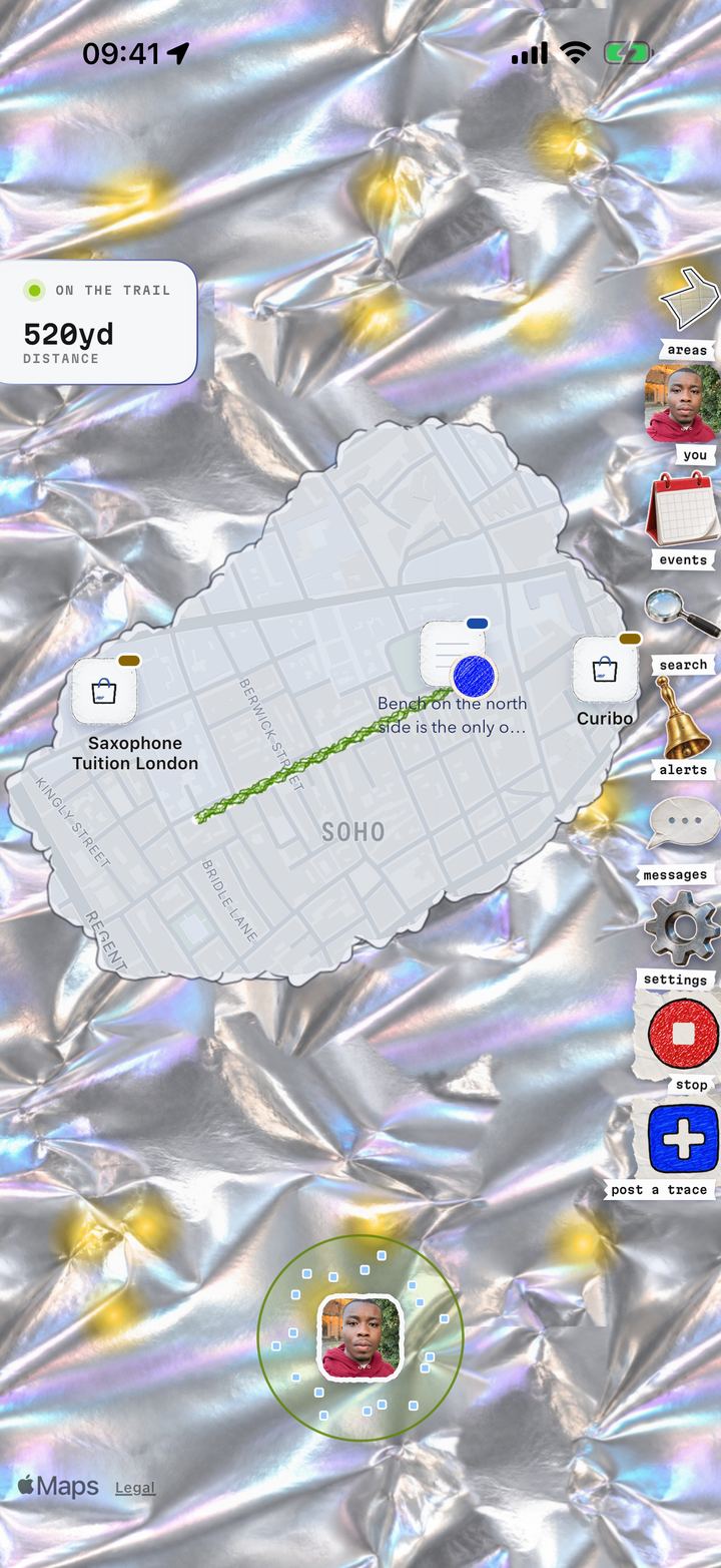 The GoBe map of Soho under iridescent foil, torn open along a walk, with a green trail running through the cleared streets